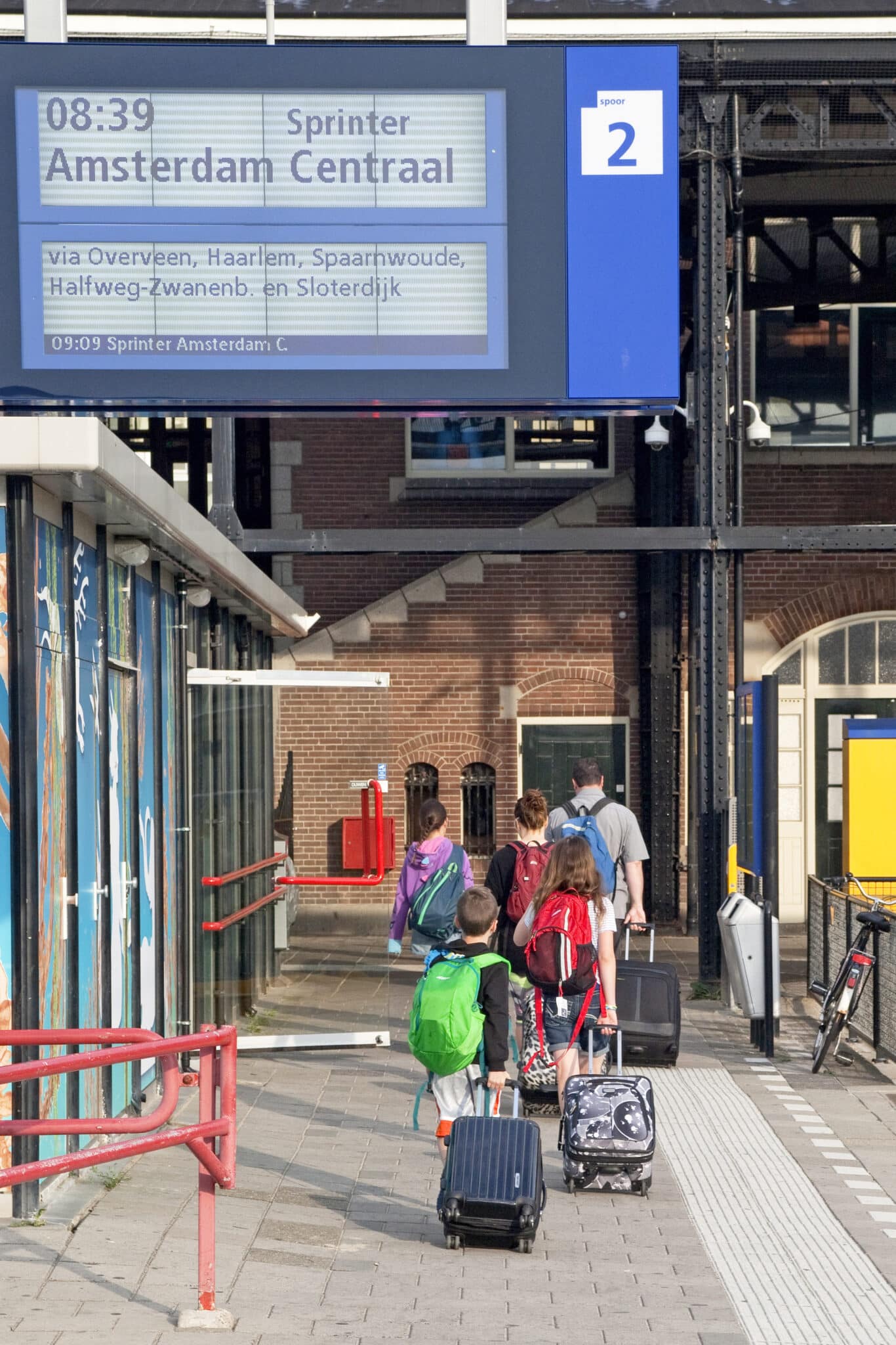 Toeristengezin met koffers wandelend op Station Zandvoort aan Zee