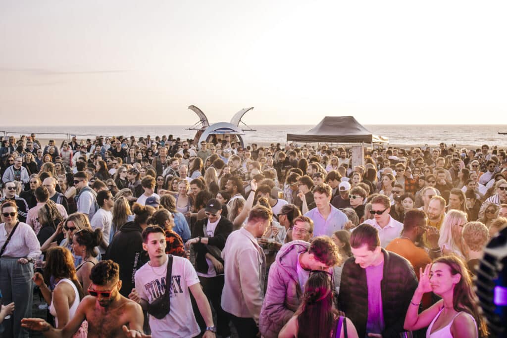 Feestende mensen met de zee op de achtergrond tijdens het evenement Zandvoort Alive.